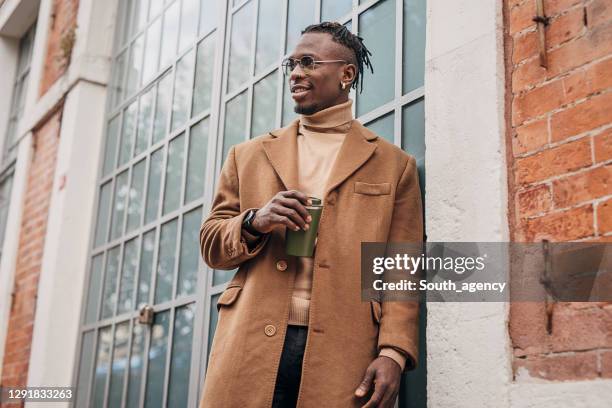 modern african-american man drinking take away coffee outdoors in the city - black coat stock pictures, royalty-free photos & images