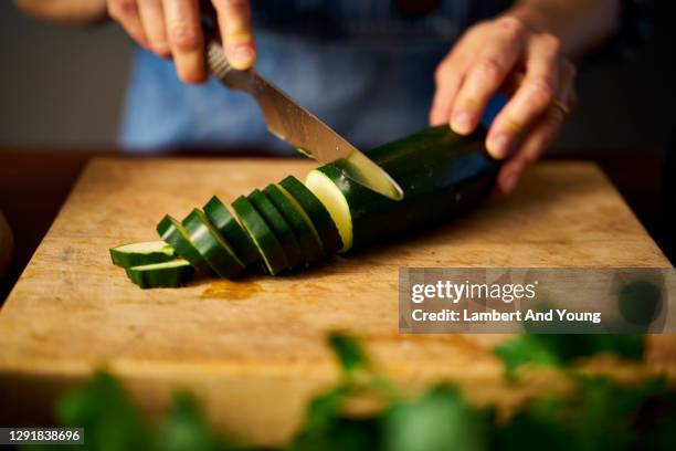 close up of slicing a zucchini on a rustic chopping board - chopping stock pictures, royalty-free photos & images