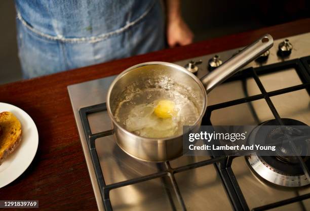 egg poaching in a pan of boiling water - gepocheerd stockfoto's en -beelden