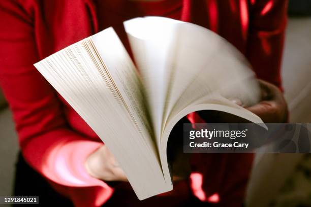 woman flips through pages in book - sfogliare libro foto e immagini stock