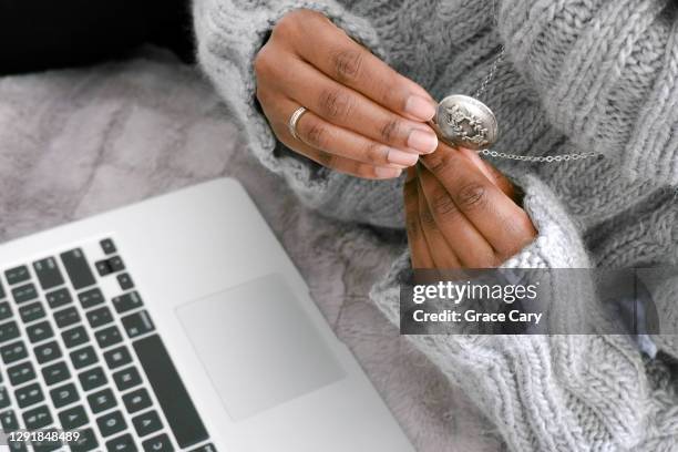 woman looks inside locket while working on laptop - silver clothes stock pictures, royalty-free photos & images