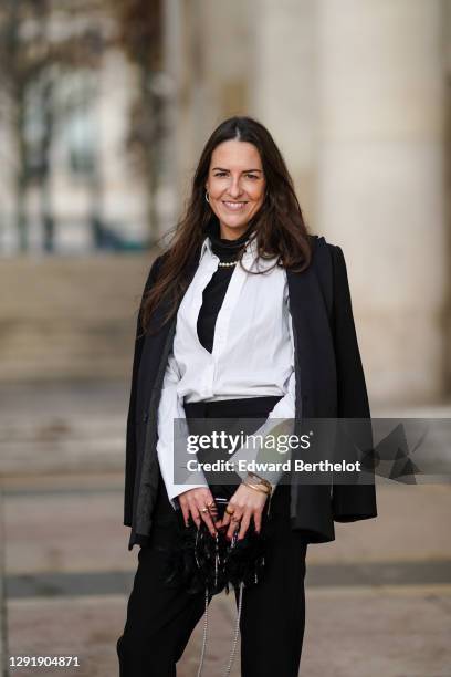 Alba Garavito Torre wears earrings, a black turtleneck top, a beaded pearls necklace, a white shirt, a black oversized blazer jacket, a black fluffy...
