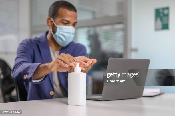 homem higienizando as mãos com gel anticóvido - hand sanitiser - fotografias e filmes do acervo