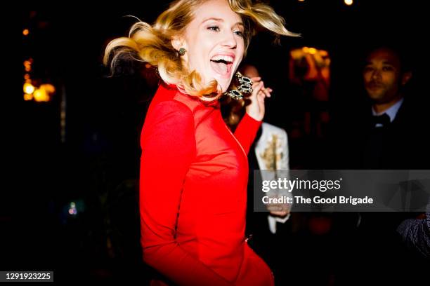 beautiful blond woman dancing by friends at back yard during garden party - rode jurk stockfoto's en -beelden