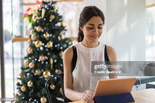business woman working in office with christmas tree behind - seville christmas stock pictures, royalty-free photos & images