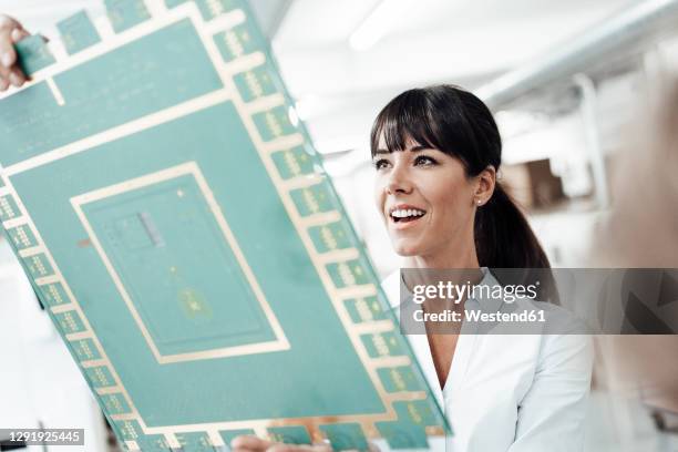 smiling businesswoman analyzing large computer chip in industry - femme frange photos et images de collection