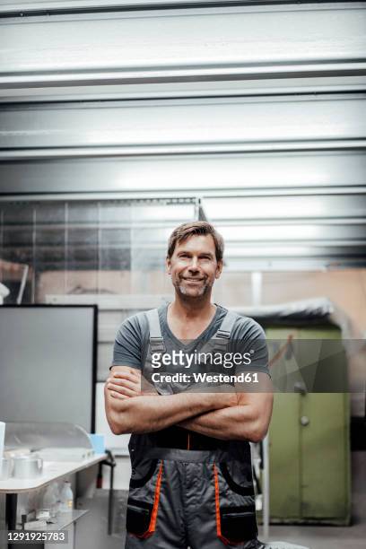 confident male worker standing with arms crossed in industry - artisan photos et images de collection