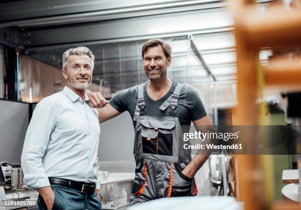 smiling mature male engineer and worker over document in industry - hand on shoulder stock pictures, royalty-free photos & images