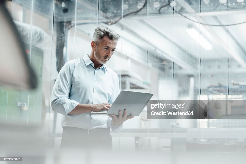 Thoughtful Male Engineer Using Laptop While Standing In Industry High ...