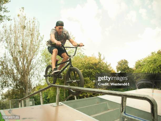 young caucasian bmx biker practicing at skateboard park - railing stock pictures, royalty-free photos & images