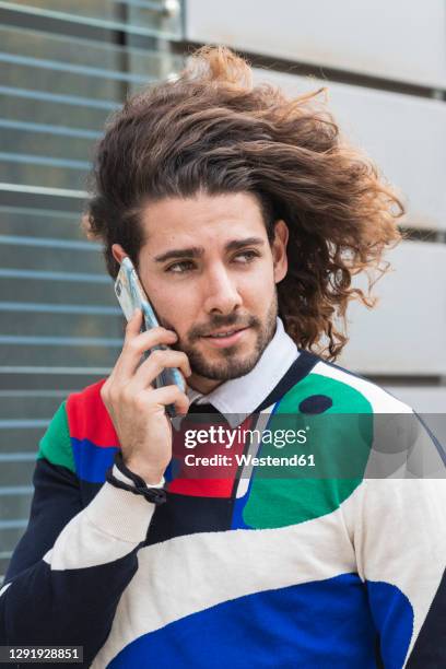 young man talking on smart phone in city - long hair wind stock pictures, royalty-free photos & images