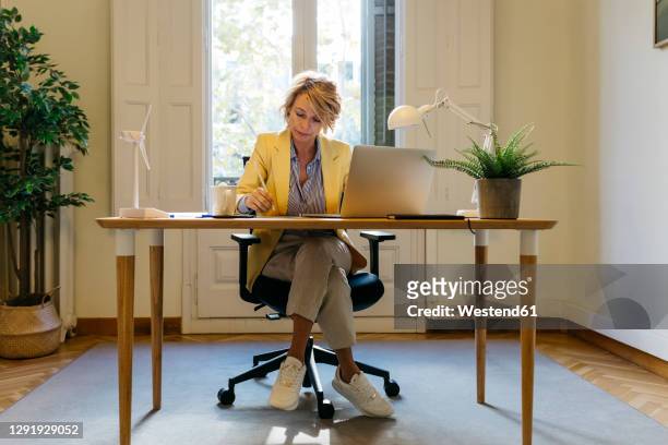 female architect sitting with laptop while working at office - überkreuzte beine stock-fotos und bilder