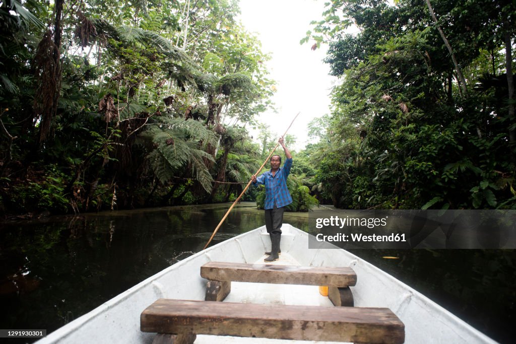 Senior Guarani man oaring in canoe at Napo River, Ecuador