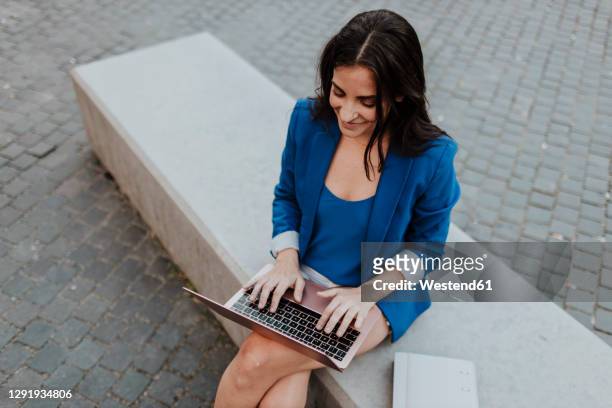 businesswoman using laptop while sitting on bench - blue blazer stock pictures, royalty-free photos & images