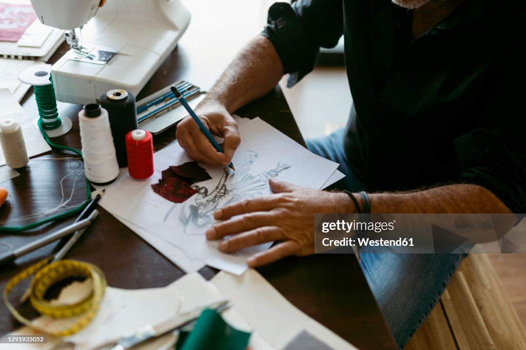 Costume designer making sketch on paper at table in work studio