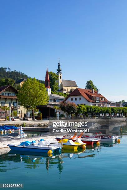 austria, upper austria, attersee am attersee, pedal boats moored in marina of lakeshore village in summer - attersee stock pictures, royalty-free photos & images