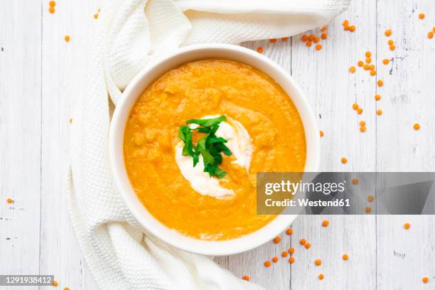 bowl of vegetarian lentil soup with carrots, orange juice, cremefraicheand parsley - soupe de légumes photos et images de collection