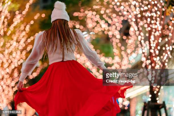 young woman happily dancing in street at night - embellished skirt stock pictures, royalty-free photos & images