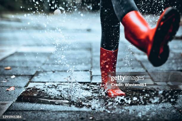 feet of little girl wearing rubber boots stepping on small puddle - rubber boot stock pictures, royalty-free photos & images