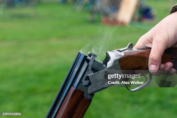 close up of person holding a shotgun with smoke - feuerwaffen abzug stock-fotos und bilder