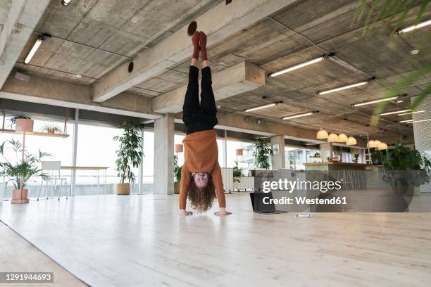 mid adult man doing hand stand in living room at home - computer work life balance stock-fotos und bilder