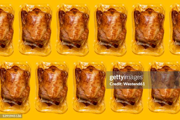 vacuum packed roasted chickens on yellow background - vacuum stockfoto's en -beelden