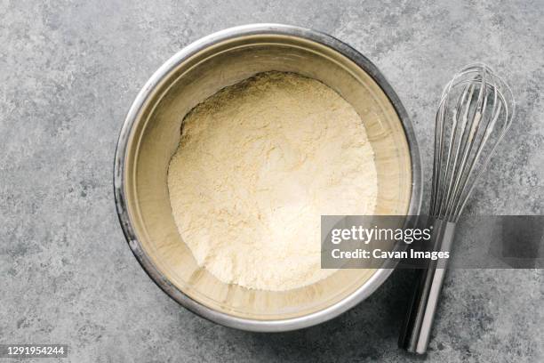 cornmeal mix in a stainless steel bowl with a wire whisk - harina de maíz fotografías e imágenes de stock