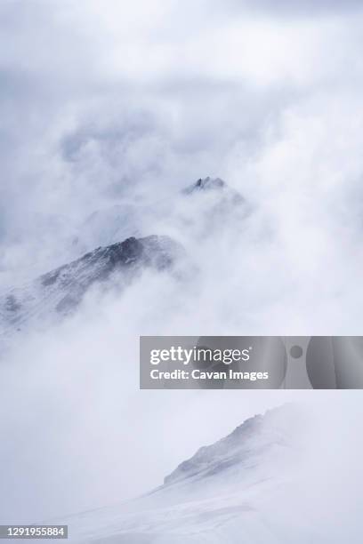 snowcapped mountain peaks in the andes covered with fog, rainbow mountain trail, pitumarca, peru - vinicunca fotografías e imágenes de stock