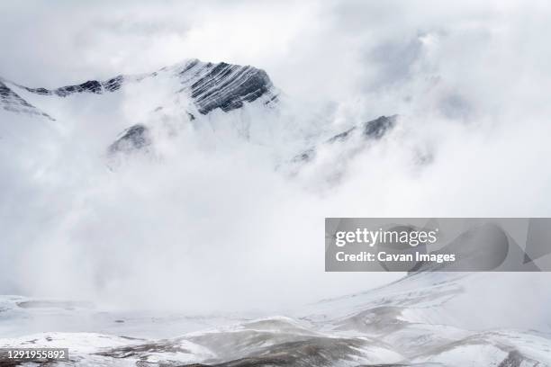 snowcapped mountain peaks in the andes covered with fog, rainbow mountain trail, pitumarca, peru - vinicunca fotografías e imágenes de stock