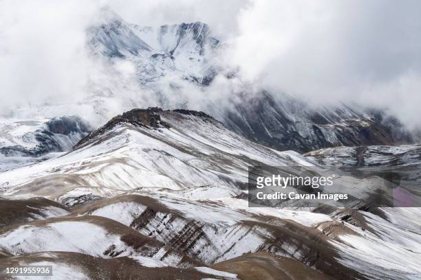 snowcapped mountain peaks in the andes covered with fog rising above the valley, rainbow mountain trail, pitumarca, peru - vinicunca fotografías e imágenes de stock