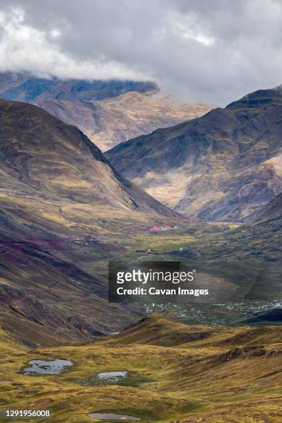 scenic view of valley amongst high andes mountains on rainbow mountain trail, pitumarca, peru - vinicunca fotografías e imágenes de stock