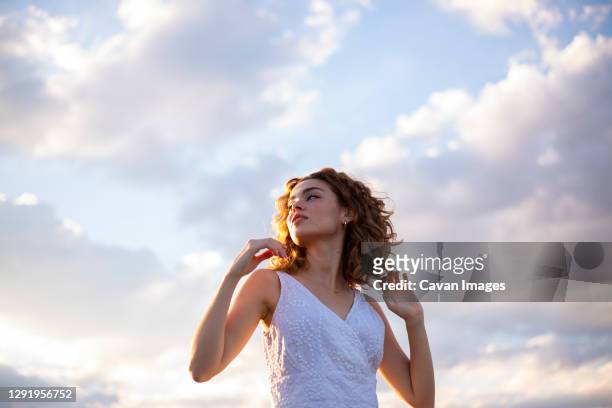 curly hair woman outdoors sky background - woman hair style fotografías e imágenes de stock