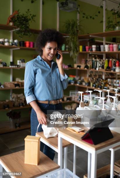 black woman speaking with client on phone in eco shop - cosmetics counter stock pictures, royalty-free photos & images