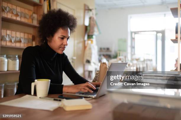 smart black entrepreneur using laptop in shop - black business owner ストックフォトと画像