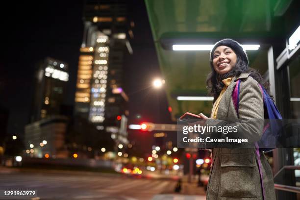 smiling woman standing using his cellphone in the street at night - mexico city night stock pictures, royalty-free photos & images