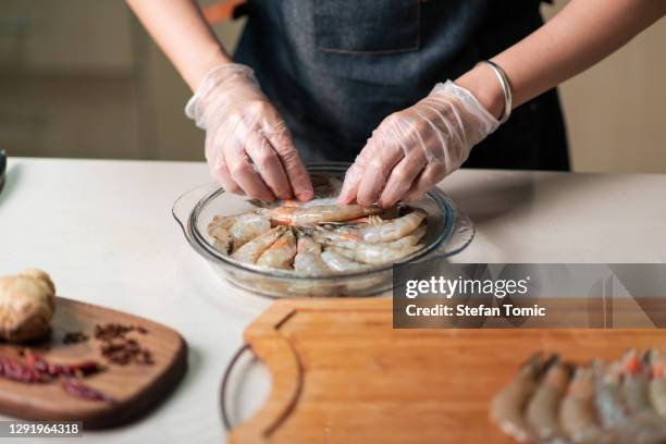 donna che ordina gamberi freschi per cucinare nella ciotola di vetro - shrimp foto e immagini stock