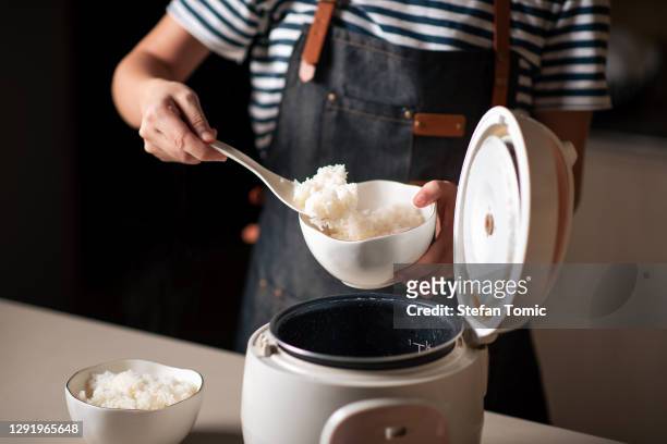 donna che toglie e serve riso bollito fresco dal fornello - rice grain foto e immagini stock