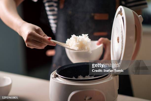 woman taking out and serving fresh boiled rice from the cooker - hot arabian women stock pictures, royalty-free photos & images