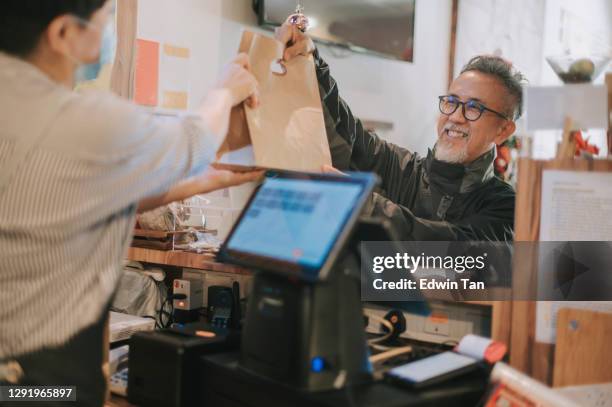 side hustle asian chinese senior man delivery picking up take away food from cashier - take away food courier stock pictures, royalty-free photos & images