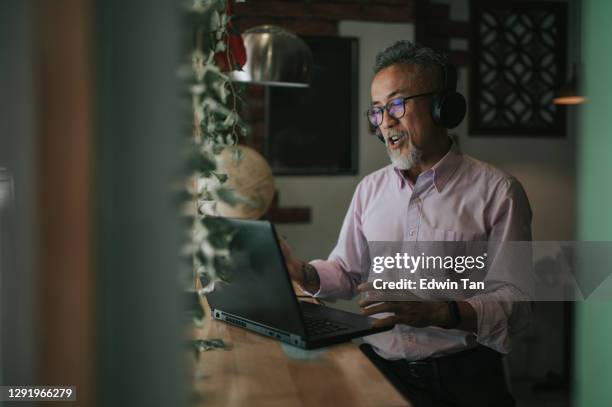 asian chinese senior man having discussion with his colleague via online virtual meeting in a cafe - corporate virtual event stock pictures, royalty-free photos & images
