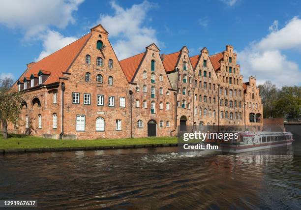 historic salt store buildings with sightseeing boat on the obertrave river (schleswig-holstein/ germany) - lübeck stock-fotos und bilder