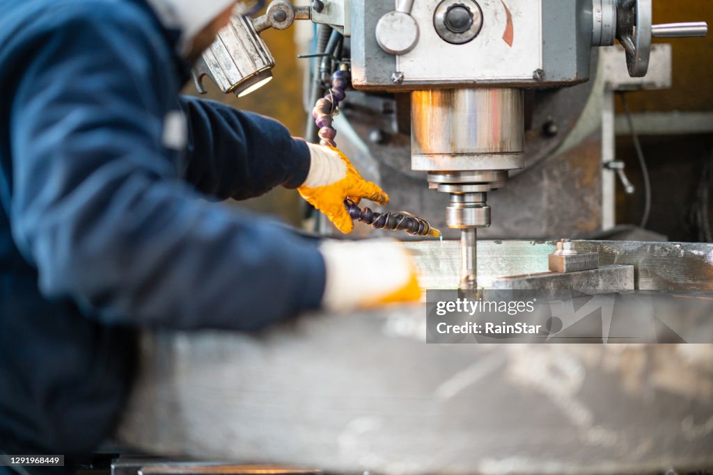 Um trabalhador em uma fábrica trabalhando em uma máquina de fresagem tradicional