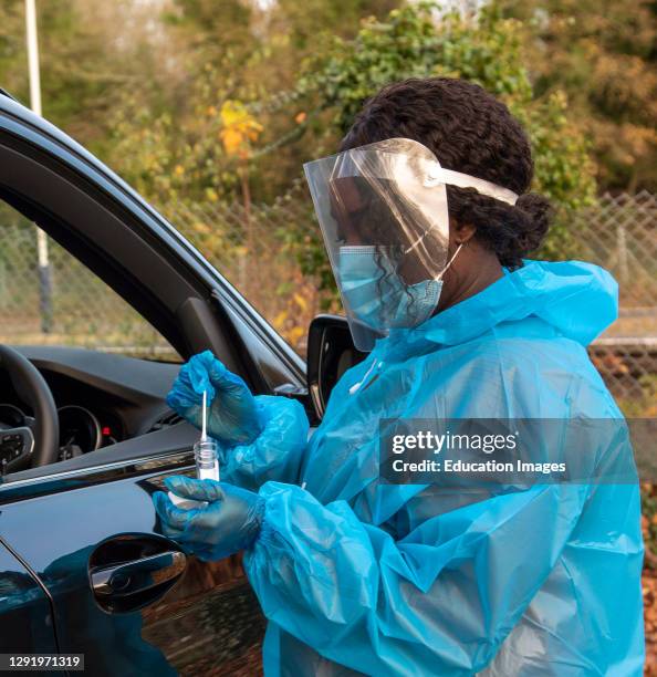 Southern England, UK, A member of staff at Covid-19 testing centre placing swab into plastic container after testing a client.