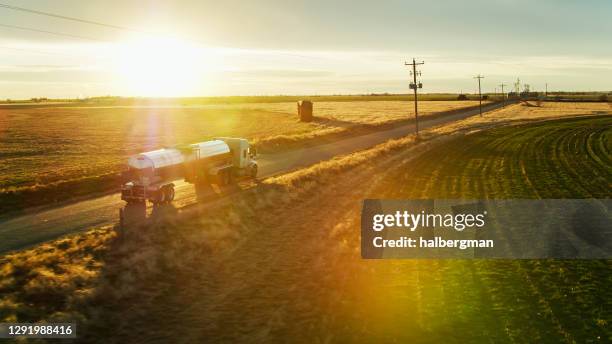 disparo aéreo de leche tanquero en country road con dramatic lens flare - granja lechera fotografías e imágenes de stock