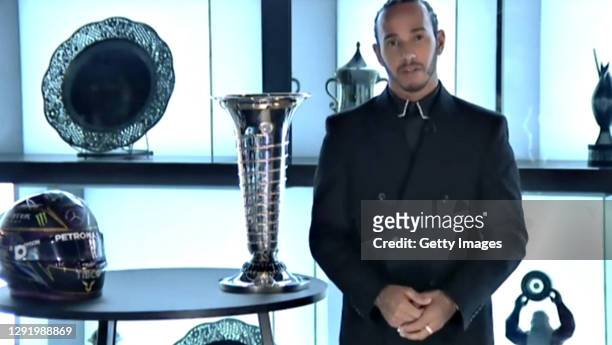 In this screengrab 2020 Formula One World Drivers Champion Lewis Hamilton of Great Britain and Mercedes GP is presented with his trophy during the...