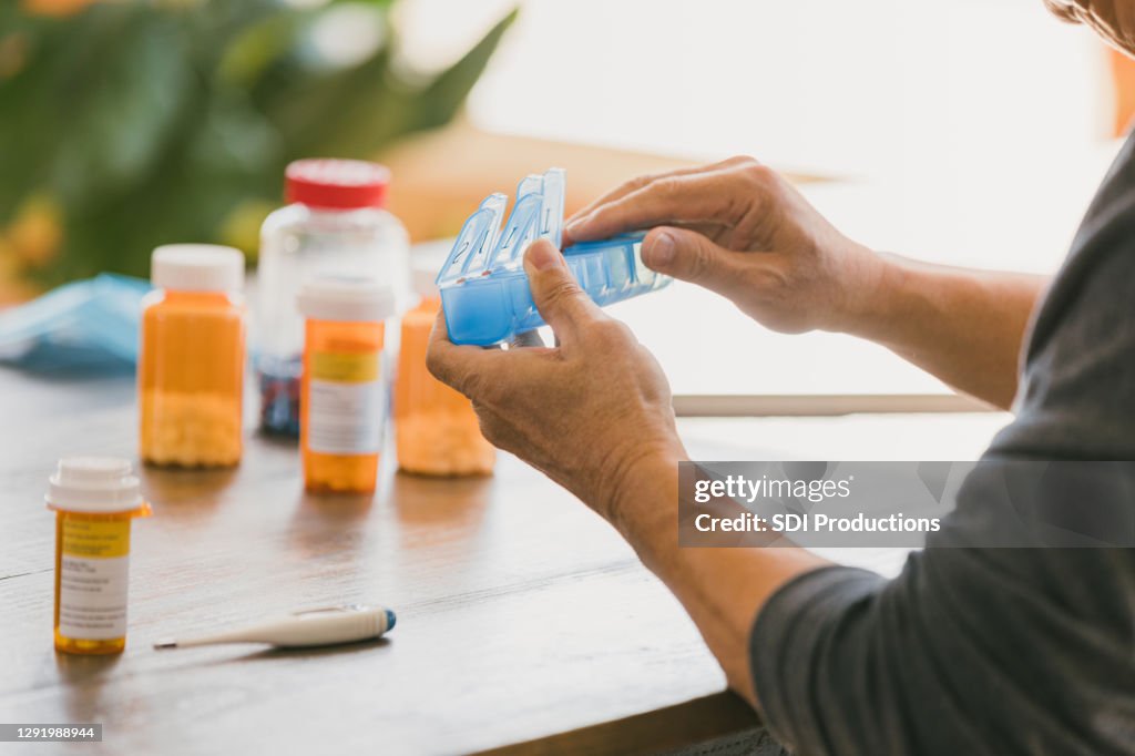 Onherkenbare man sluit pillendoos na het organiseren van zijn medicijnen
