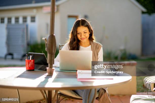 latino woman on laptop working from home in backyard - makeshift office stock pictures, royalty-free photos & images