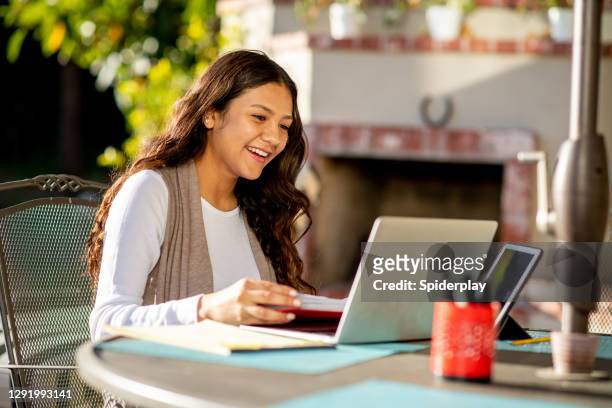 femme latino sur l’ordinateur portatif travaillant de la maison dans l’arrière-cour - une seule adolescente photos et images de collection