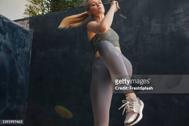 active lifestyle: confident blonde woman doing knee-to-elbow exercise - touching elbows stock pictures, royalty-free photos & images
