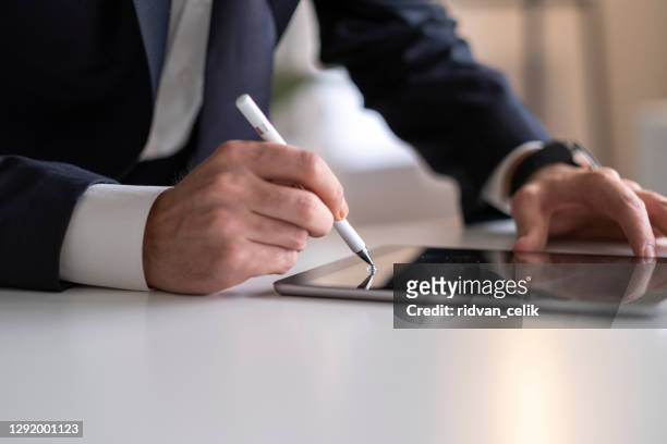 businessman signing digital contract on tablet using stylus pen - human body part stock pictures, royalty-free photos & images